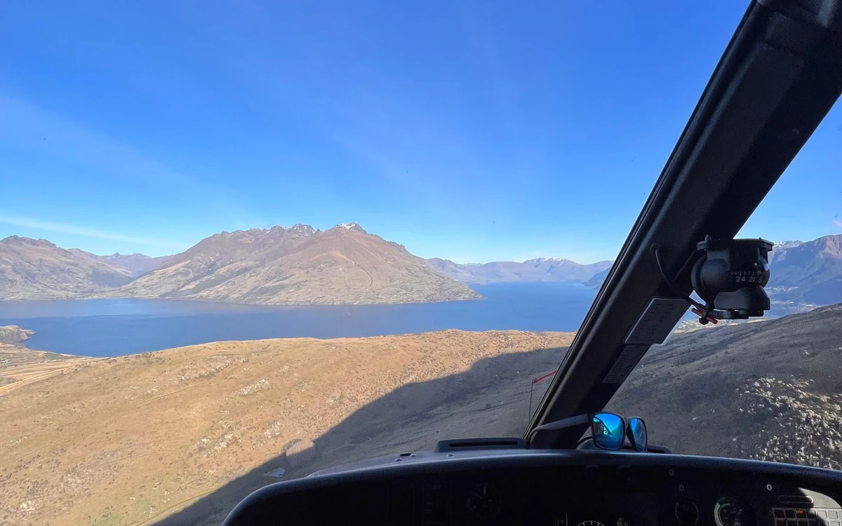View forward from a helicopter cabin over a snow-covered mountain range