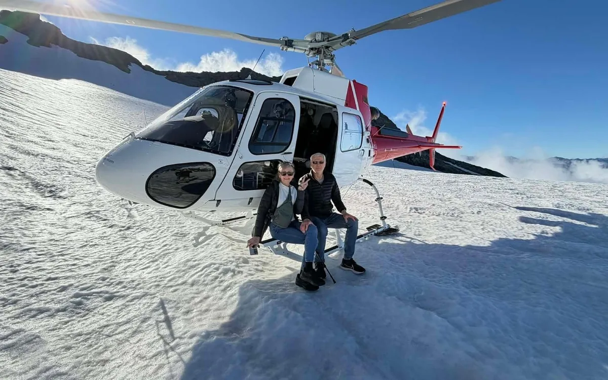 A helicopter standing on a snow-covered alpine plateau under bare rock peaks